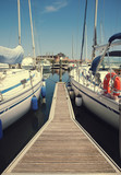 Fototapeta Pomosty - White yachts in the port waiting. On the sea is calm.