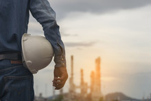 Young Engineer Holding Safety Hatstand At The Petrochemical Refinery Plant. Petrochemical Engineer Or Worker Or Foreman Looking At Refinery Plant. Petrochemical Engineering, Foreman And Worker Concept