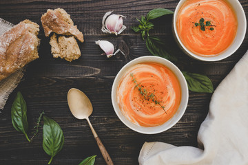 Tomato cream soup with bread on the wooden table, top view