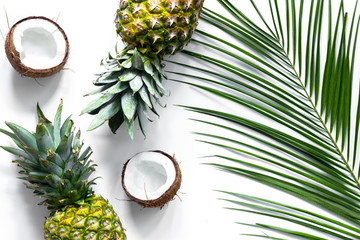  Concept of summer tropical fruits. Pineapple, cocount and palm branch on white background top view