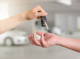 Male hand holding a car key and handing it over to another person