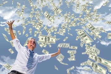 Excited business man with money rain against sky