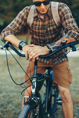 Poster - Young Man Cyclist In Sunglasses With Bicycle In Summer Park During Sunset Vacation Traveling Relaxation Resting Concept