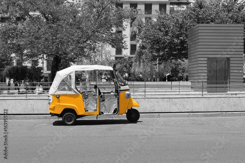 black-and-white-picture-of-tuk-tuk-small-passenger-three-weel-mini-car-isolated-on-summer-empty-street-road-background-bright-yellow-rickshaw-helps-tourists-to-travel-around-the-city-fast