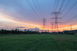 © trongnguyen - Group silhouette transmission towers (steel lattice/power tower, electricity pylon) next to apartment complex at sunset in US. Texture high voltage pillar, overhead power line, industrial background.