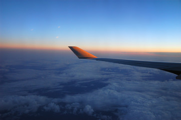 Wall Mural - sunrise light on aerial cloud below airplane wing