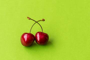 Two cherries on a green background