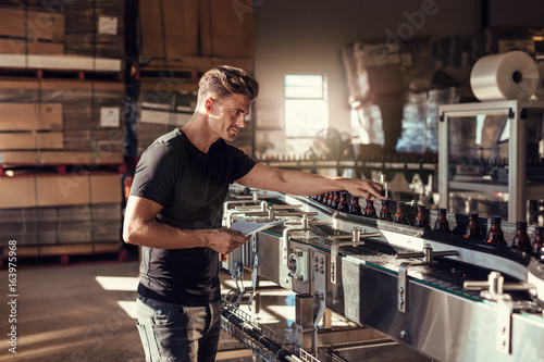 Young man supervising the beer production at brewery Canvas Print