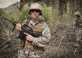 Soldier man holding a weapon against field background