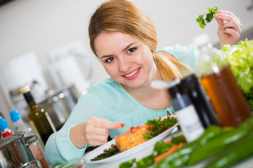 Wall Mural - Positive housewife with plate of salad in kitchen