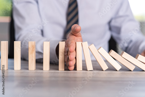 Fotomural Concept of business control by stopping domino effect