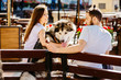 Young hipter couple with alaskan malamute dog sitting on a bench in the city. Family, pet, animal and people concept.