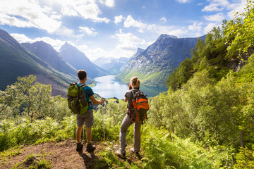 two hikers at viewpoint in mountains with lake, sunny summer