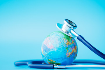 green earth day, save the wold and global healthcare concept. stethoscope wrapped around globe on bl