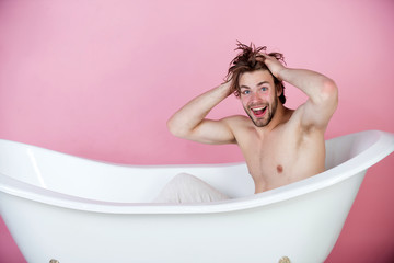 Wall Mural - handsome young man with muscular body sitting in white bathtub