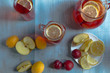 Homemade iced sweet tea with ripe apricots, plums and apples. Homemade tasty lemonade with fresh berries on a rustic wooden background