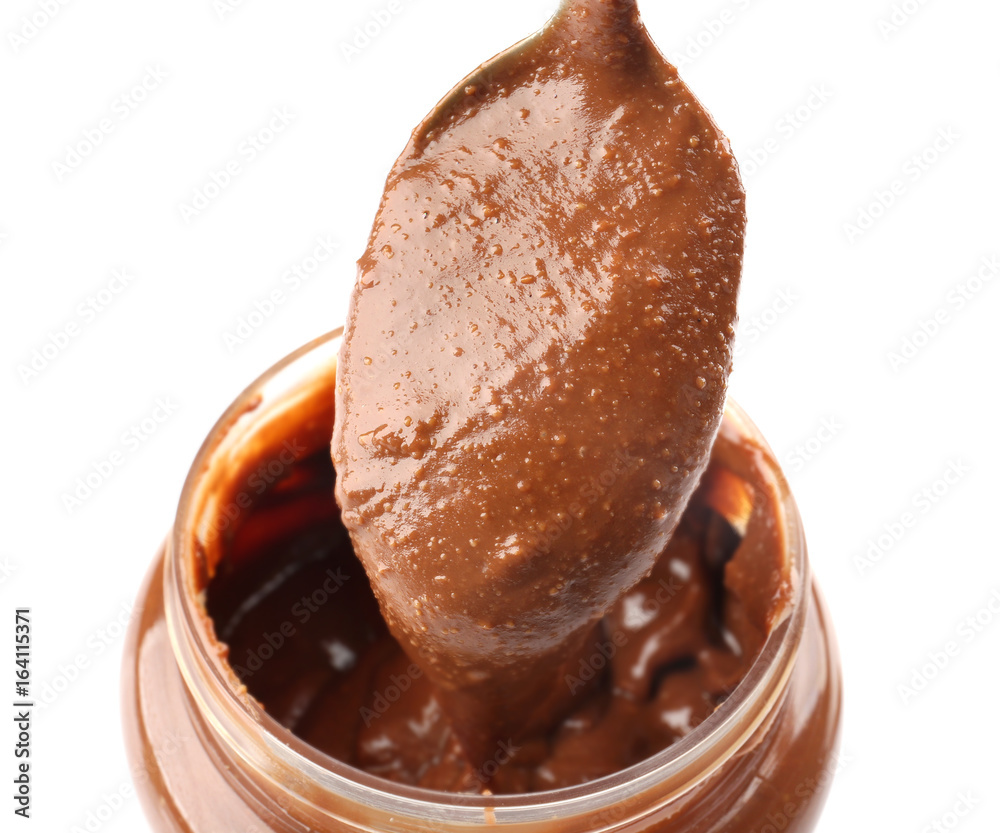 Creamy peanut butter in spoon and jar on white background