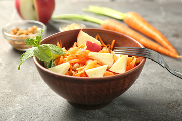 Canvas Print - Delicious carrot raisin salad with apple in brown clay bowl on table