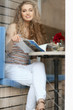 © Africa Studio - Beautiful young woman sitting in cafe and reading magazine, view from outdoors through window