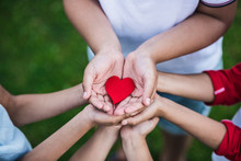 Close-up Partial View Of Children Holding Red Heart Symbol Outdoors