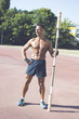 © Addoro - Closeup of a handsome middle-aged man working out on a running track. Healthy adult man holding the wooden barbell. Tanned skin and shirtless middle-aged man exercising.