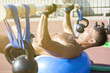 © Addoro - Handsome middle aged man working out on a running track. Healthy adult man doing push ups using a kettlebell and wooden barbell on the yoga ball. Tanned skin and shirtless middle-aged man.