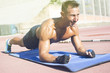 © Addoro - Handsome middle aged man working out on a running track. Healthy adult man doing plank exercise. Tanned skin and shirtless middle-aged man.