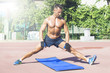 © Addoro - Handsome middle aged man working out on a running track. Healthy adult man doing stretching. Tanned skin and a shirtless middle-aged man doing a split.