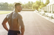 © Addoro - Handsome middle aged man working out on a running track. Healthy adult man looking at the track. Tanned skin and shirtless middle-aged man. Lens flare in the background.