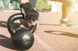 © Addoro - Close up shot of a man's hand on a kettlebell. Crossfit instructor at the track.