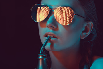 woman in sunglasses drinking soda from water bottle with straw