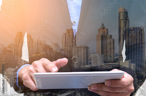 Photographie Double exposure of businessman using tablet with long exposure city night