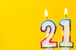 Number 21 birthday celebration candle against a bright yellow background