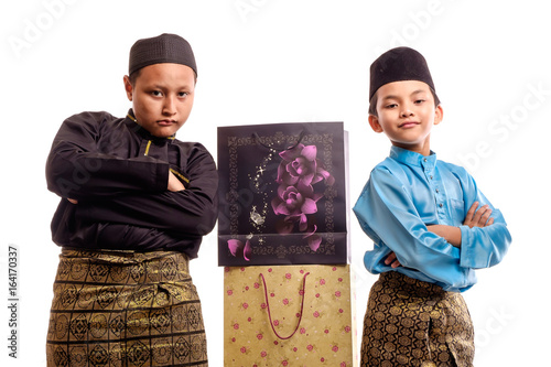 Fotografía Young Muslim boys in malay traditional clothes with shopping bags for Eid Al Fitr, isolated on white