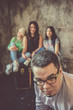 © Artem Markin - Serious young man in glasses on the background of a cheerful company of three pretty girls