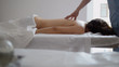 © KONSTANTIN SHISHKIN - Male physiotherapist massaging woman's back in the medical office