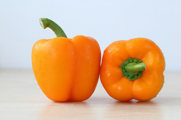 Two orange peppers on wooden board