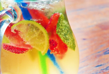 Wall Mural - Glass of homemade lemonade in cafe on the wooden table. Summer refreshing cocktail with lime, strawberry, mint leaves and vanilla. Selective focus