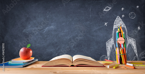Cuadros en Lienzo Start School Concept - Supplies On Desk And Rocket Drawn On Blackboard