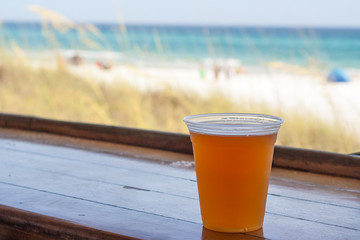 A cold beer sits on the bar with a view of the beach