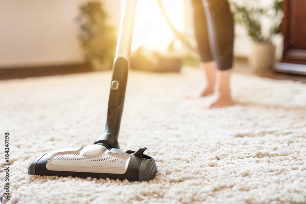 Woman using a vacuum cleaner while cleaning carpet in the house. Stock ...