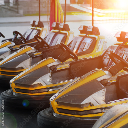 Plakat elektryczne samochodziki z rzędu w parku rozrywki rano, stonowanych w świetle słonecznym efekt z flary obiektywu