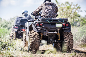 Back view of quad bike  riding along a country road.