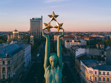 Beautiful Sunset View In Riga By The Statue Of Liberty - Milda. Freedom In Latvia. Statue Of Liberty Holding Three Stars Over The City. Latvian Spirit.