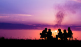 Fototapeta  - people sitting near campfire against sunset with copyspace