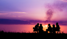 People Sitting Near Campfire Against Sunset With Copyspace