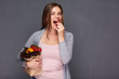 © Yuriy Shevtsov - woman holding paper bag with vegetables eating tomato.