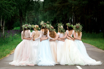 Wall Mural - Wedding. The bride in a white dress standing and embracing bridesmaids