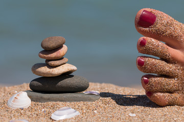 Lady 's feet relax close to zen stone tower