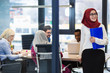 © Myvisuals - Arabian Businesswoman in office with Businesspeople meeting in the background, Arabian woman wearing Hijab in office with her colleagues in background